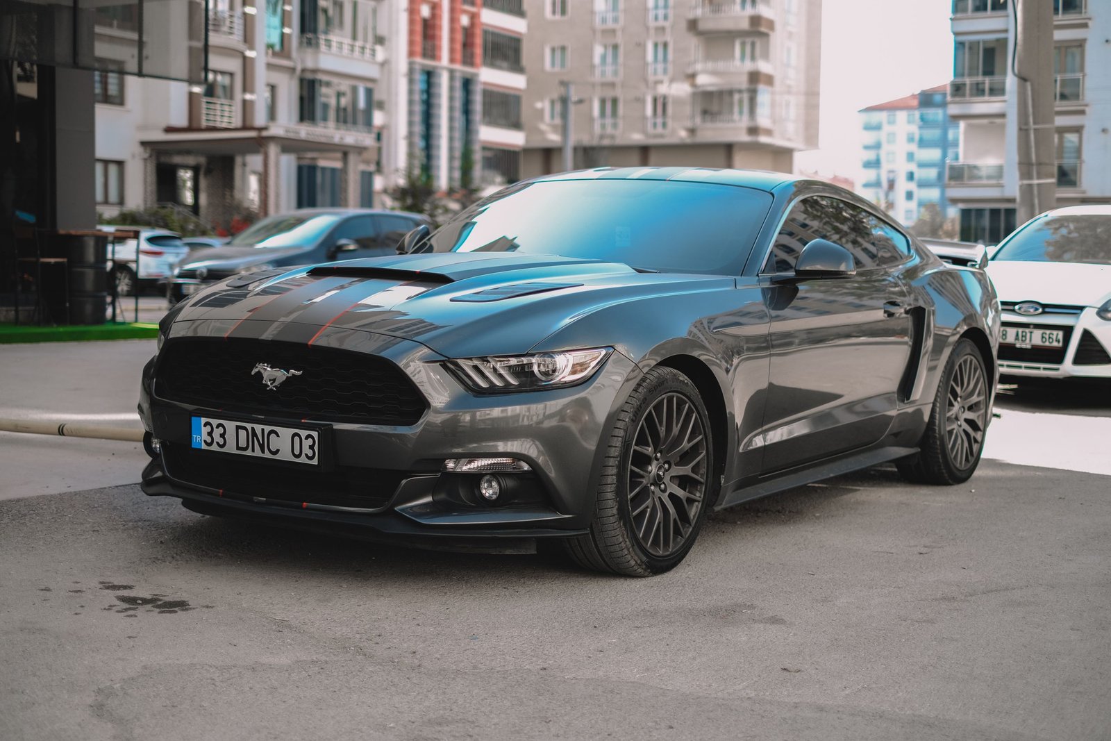 A stylish black Ford Mustang parked on a city street, showcasing its sporty design in a modern urban environment.