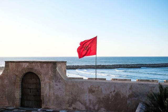 The Moroccan flag waves atop a historic fort by the sea in Rabat, offering stunning coastal views.